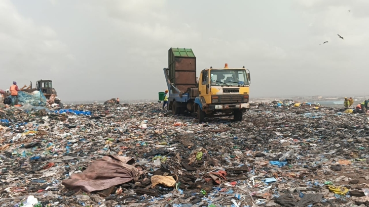 A waste disposal truck emptying a truck at the peak of the mountainous dumpsite.